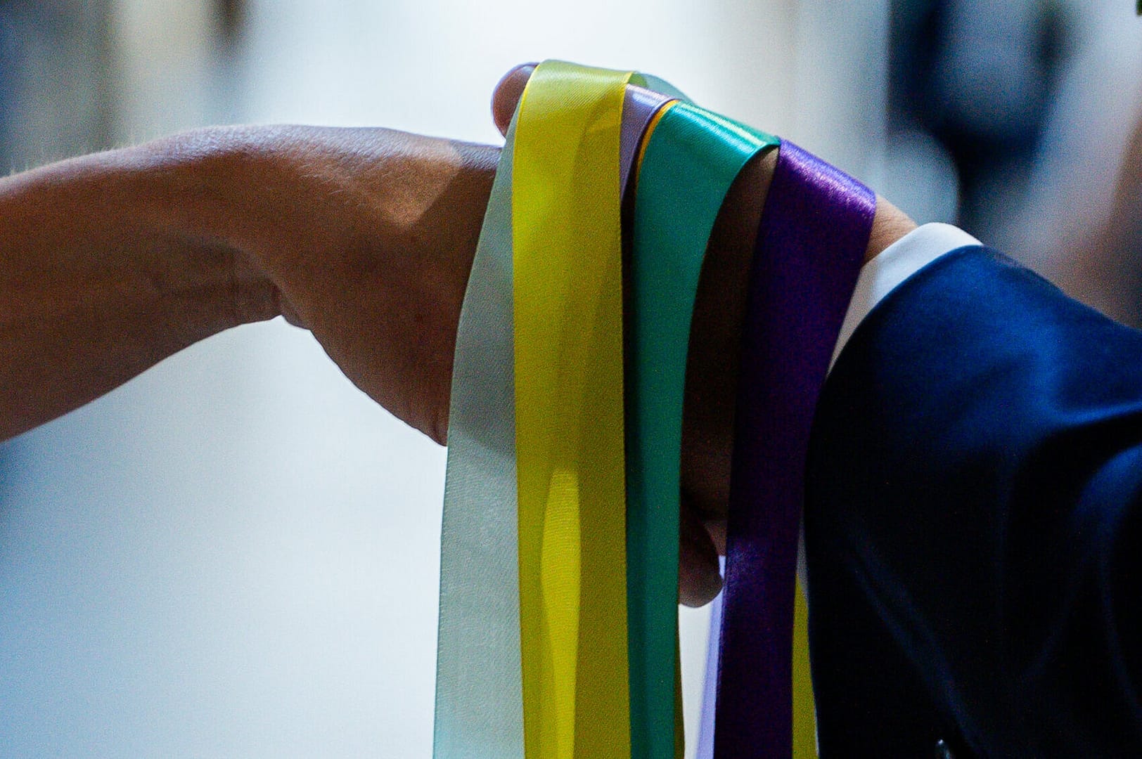 Mains d'un couple liées par des rubans colorés lors du rituel du Handfasting en cérémonie laïque